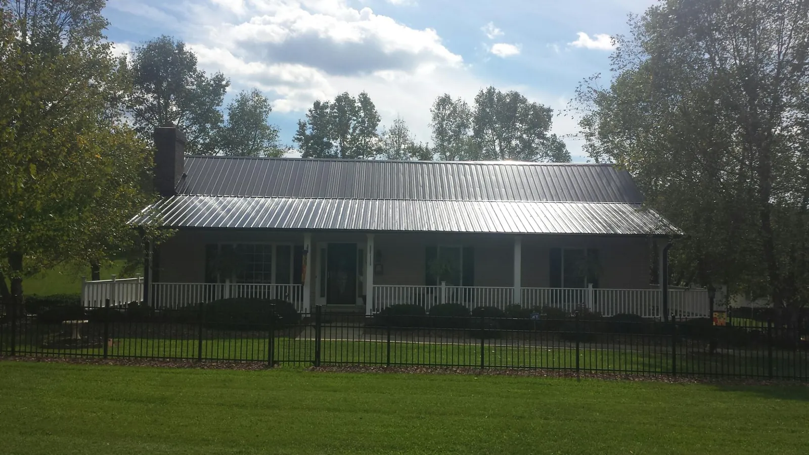 Gray metal roof on a brick ranch with a full width front porch — Gutter Guard Installation work by our crew in Bennington