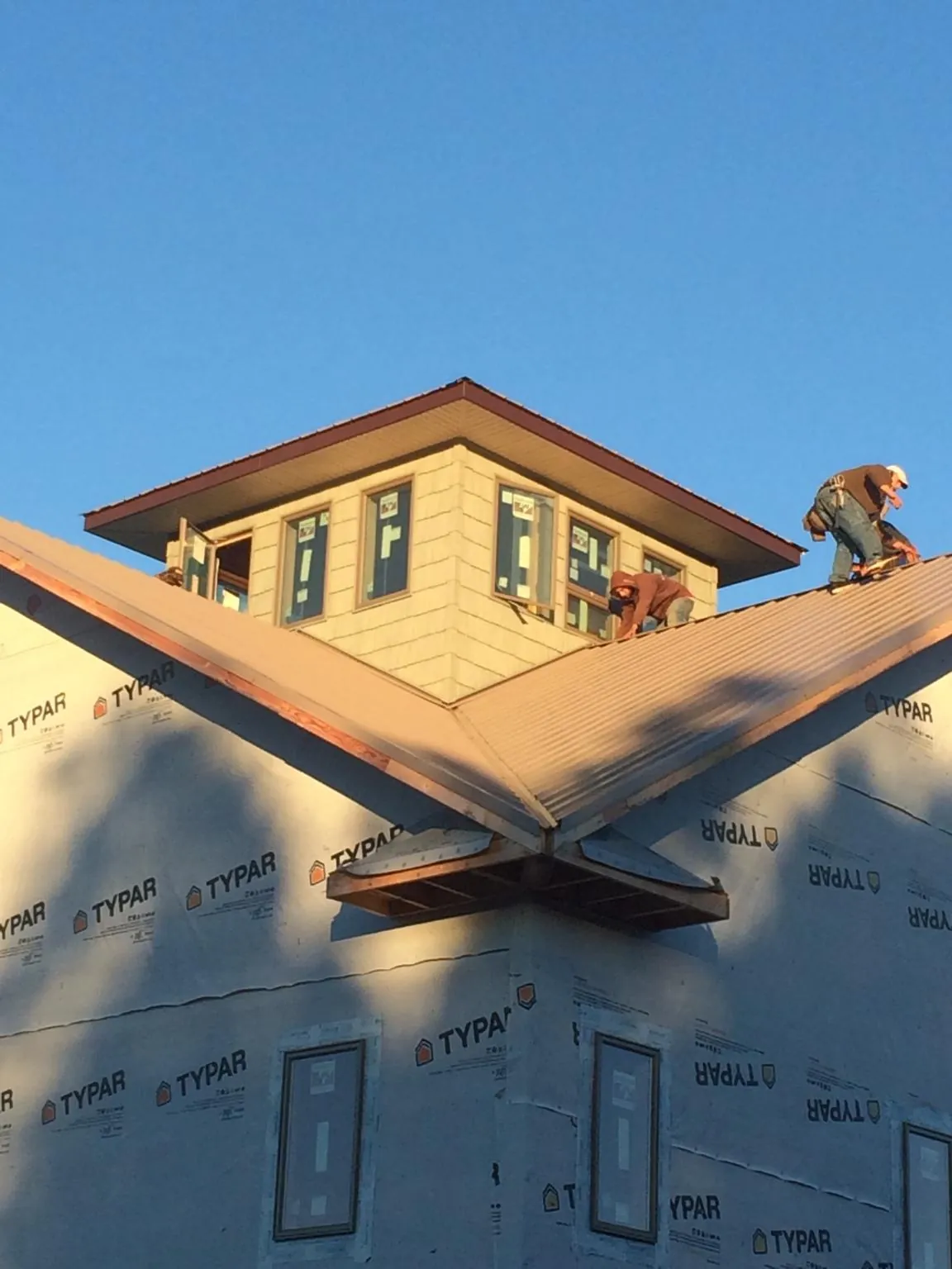 Roofers working around a rooftop cupola on a new metal roof at sunset — Roof Waterproofing in Bennington by Roofing Brothers